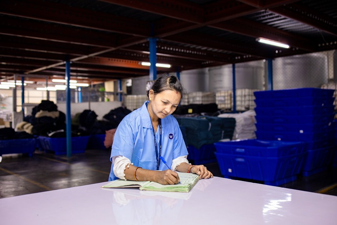 A warehouse employee in a blue shirt writing in a logbook, showing a responsive alternative for managing logistics without relying solely on technology.